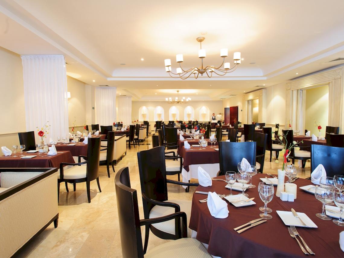 Innenansicht des Restaurants im Grand Sunset Princess All Suites Resort mit gedeckten Tischen und einer eleganten Atmosphäre.