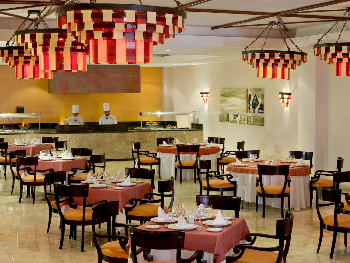 Restaurant im Grand Sunset Princess All Suites Resort mit orange Tischdecken und roten Kronleuchtern.