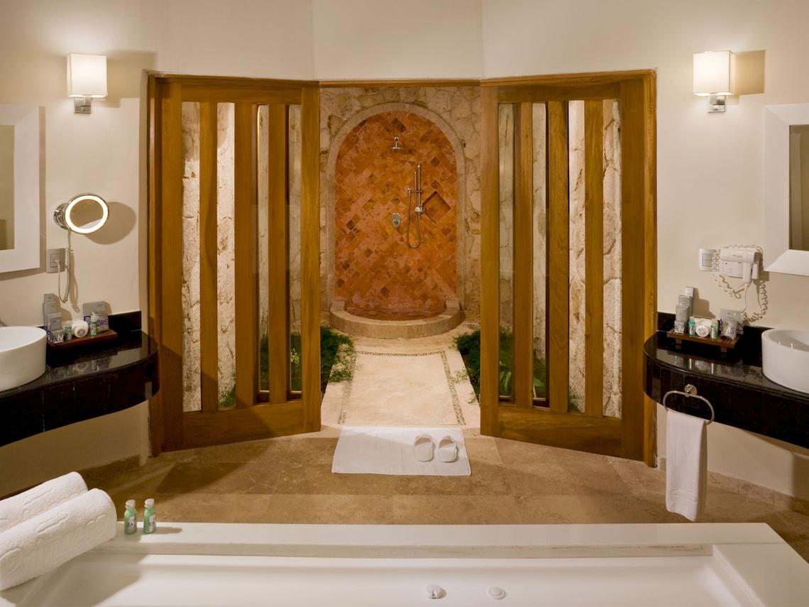 Badezimmer des Grand Sunset Princess All Suites Resorts mit Badewanne, separater Dusche und Holztüren.