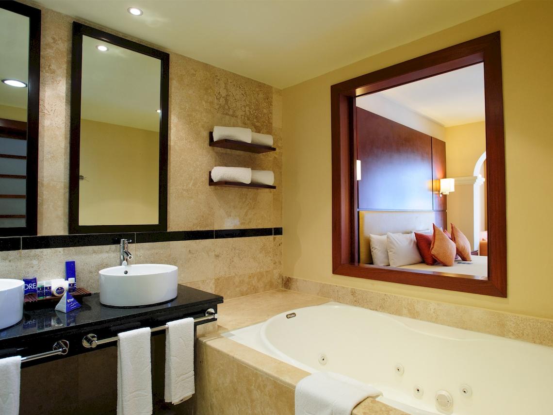Badezimmer im Grand Sunset Princess All Suites Resort mit Badewanne, Waschbecken und Spiegeln.