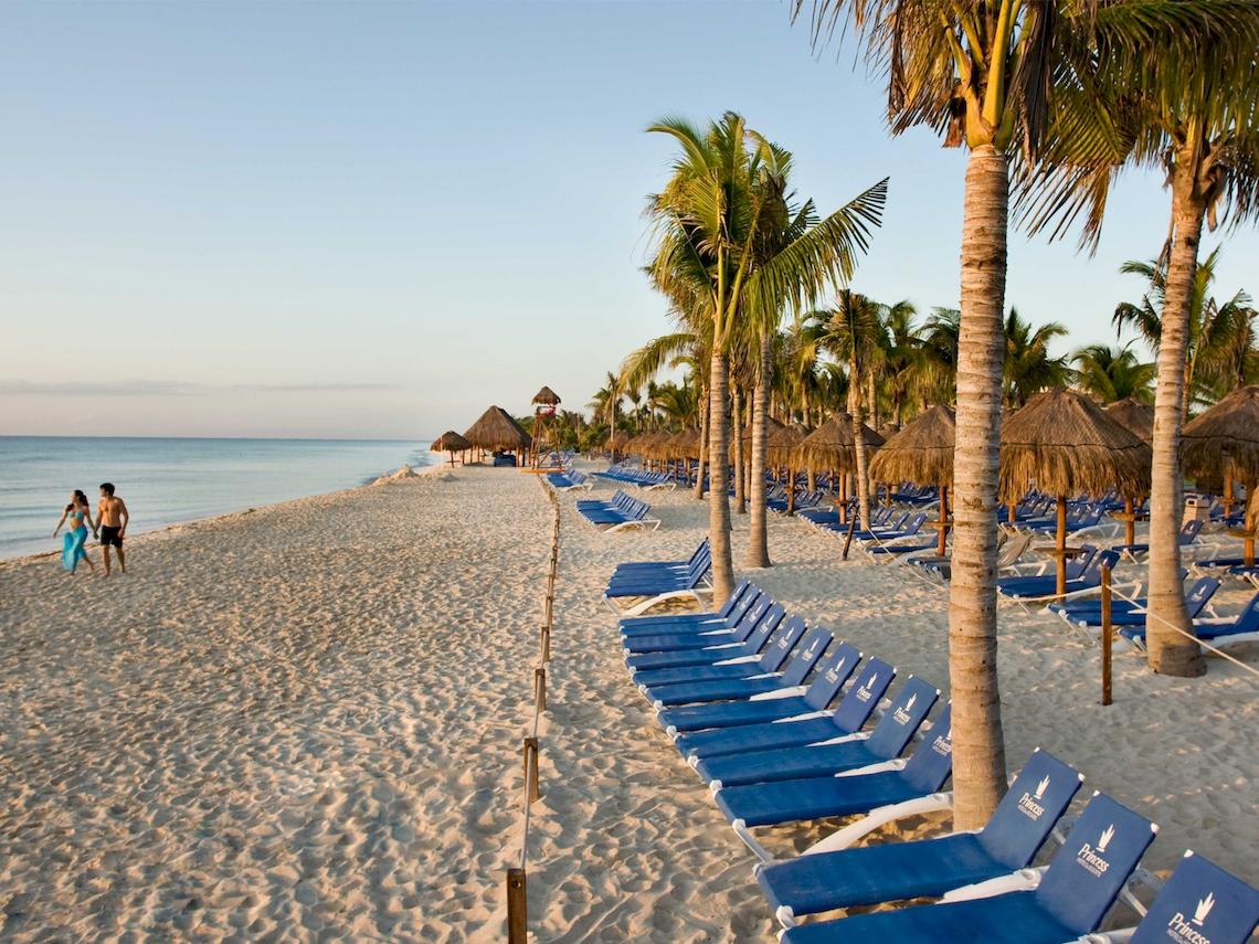 Strand mit blauen Sonnenliegen und Palmen am Grand Sunset Princess All Suites Resort