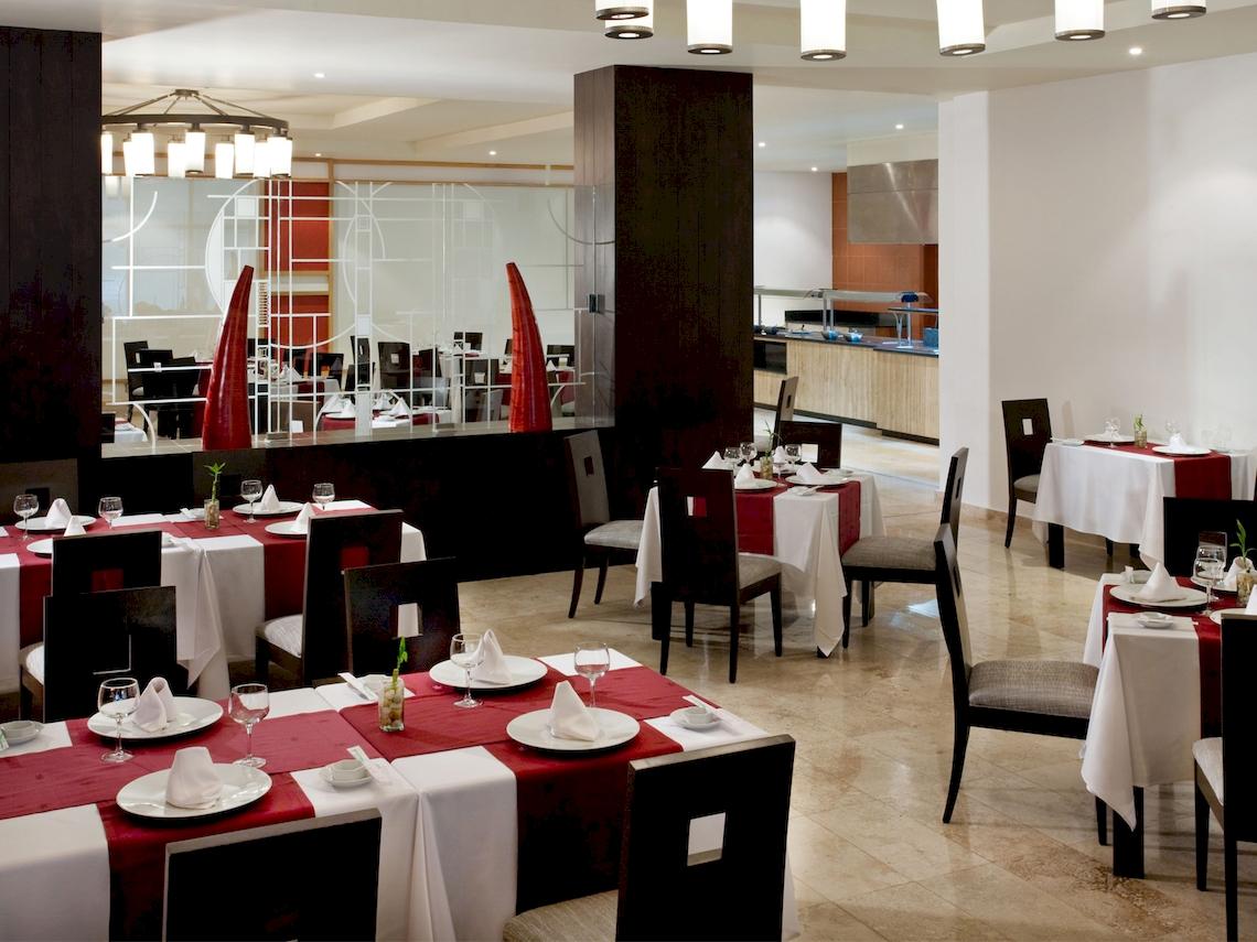 Innenansicht des Restaurants im Grand Sunset Princess All Suites Resort mit elegant gedeckten Tischen und Stühlen.