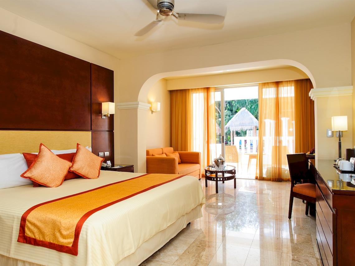 Suite-Zimmer im Grand Sunset Princess All Suites Resort mit Bett, Sofa und Blick auf den Garten.