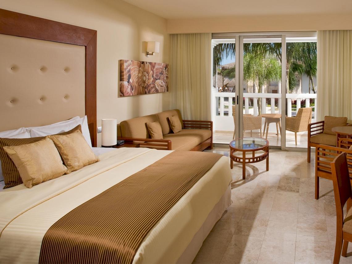 Schlafzimmer im Grand Sunset Princess All Suites Resort mit einem großen Bett, Sofa und Terrassentür.