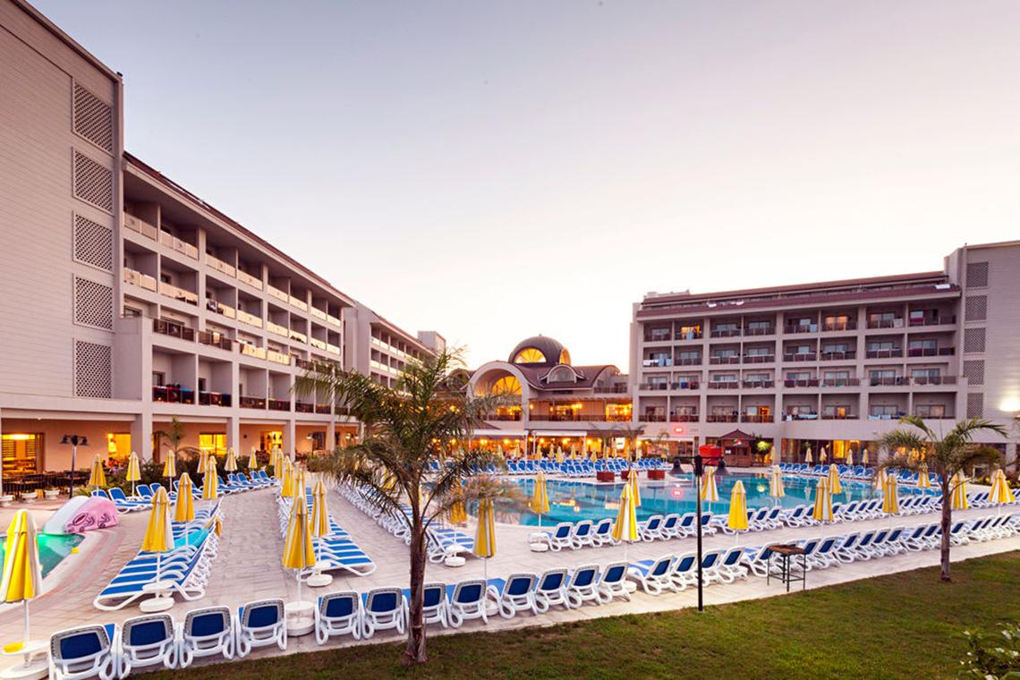 Außenbereich des Seher Sun Palace Resorts und Spa mit Swimmingpool und Sonnenliegen.