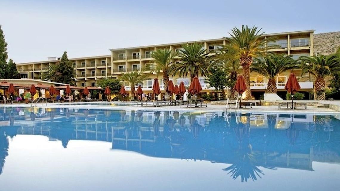 Außenpool des Doryssa Seaside Resort mit roten Sonnenschirmen und Palmen