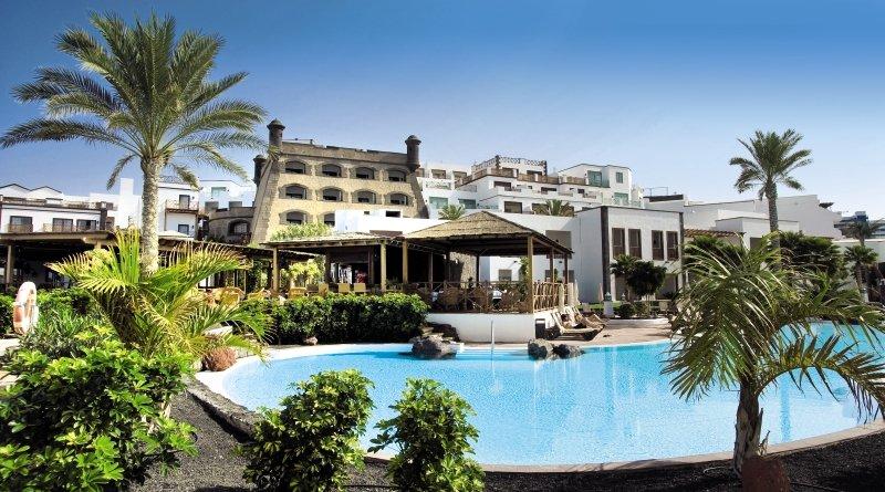 Außenpool des Gran Castillo Tagoro Family & Fun Hotels mit Palmen und Gebäuden im Hintergrund.
