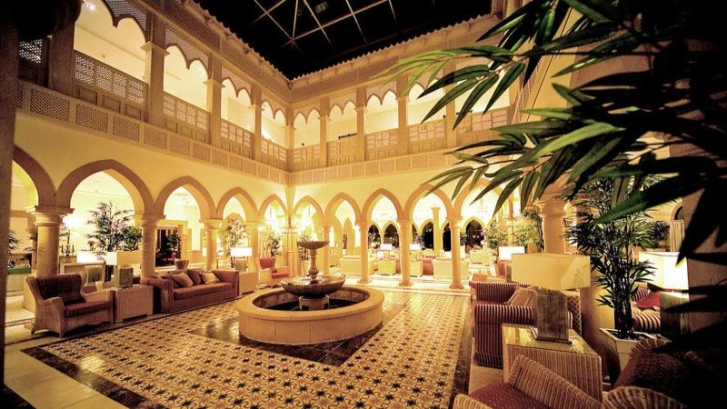 Das elegante Foyer des Gran Castillo Tagoro Family & Fun Hotels mit einem Brunnen, Sitzgelegenheiten und Pflanzen.