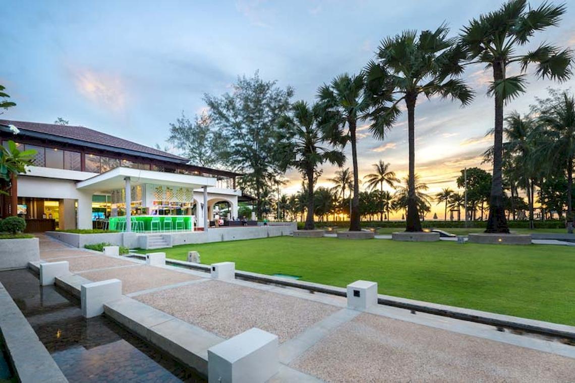 Außenansicht des Katathani Phuket Beach Resorts mit gepflegtem Rasen und Palmen