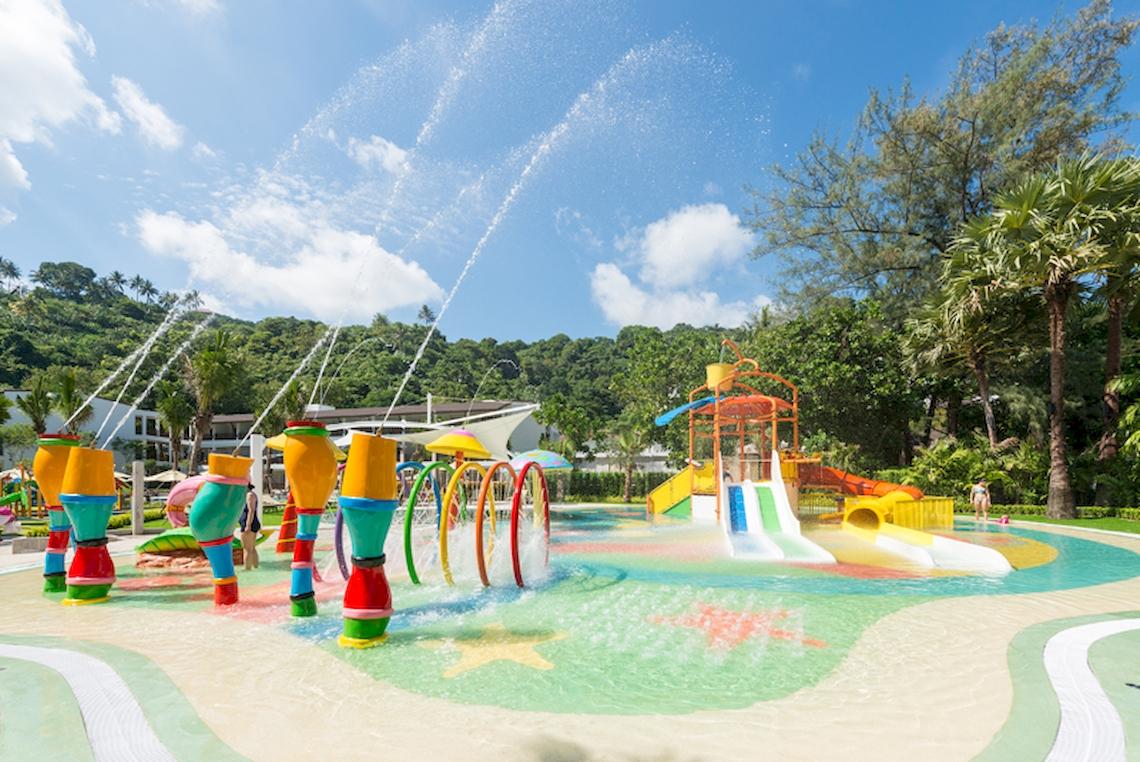 Wasserspielplatz im Katathani Phuket Beach Resort mit bunten Wassersprühen und Rutschbahnen.