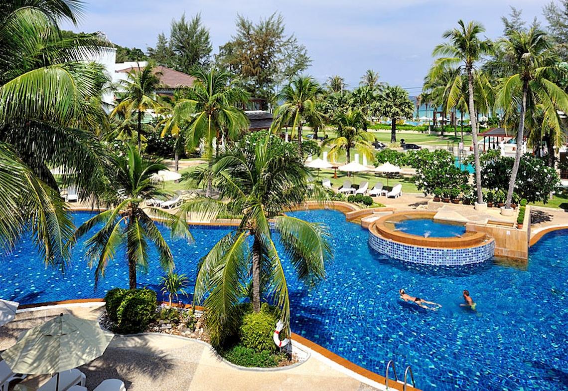 Außenansicht des Katathani Phuket Beach Resort Pools mit zwei Schwimmern und üppiger Palmenbepflanzung.