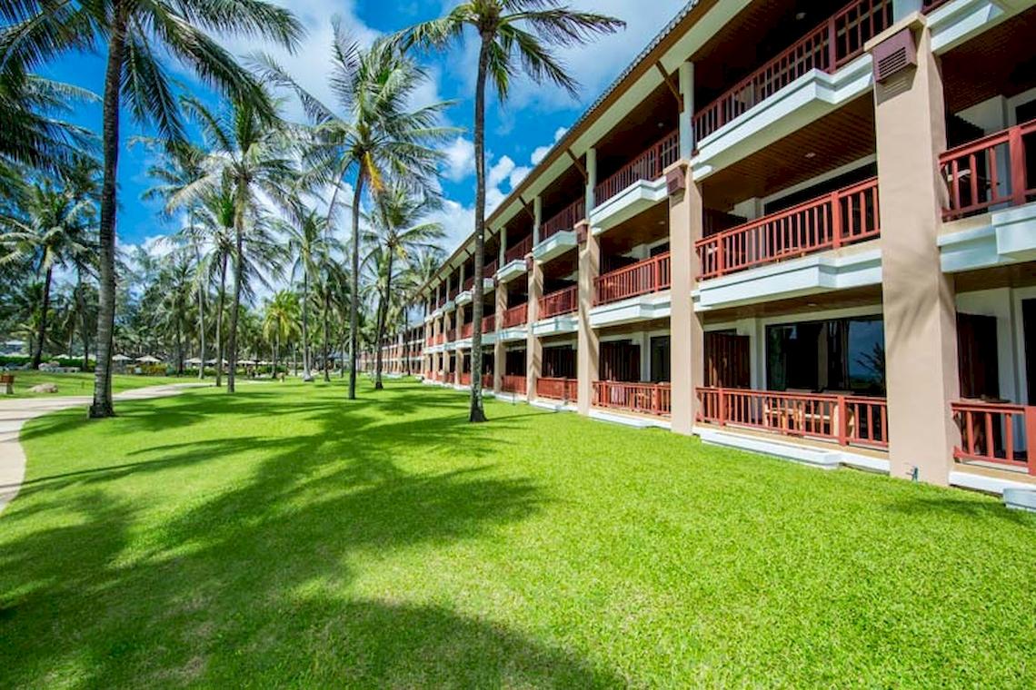 Außenansicht des Katathani Phuket Beach Resorts mit Rasen und Palmen im Vordergrund