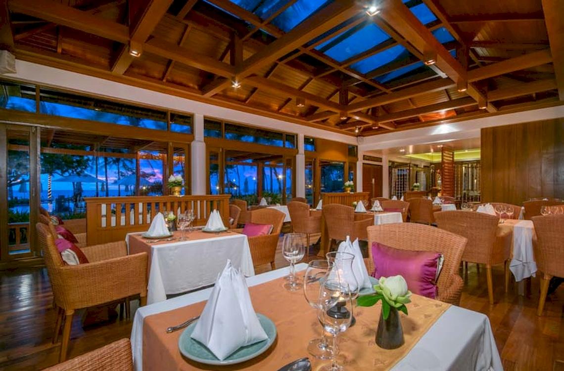 Innenansicht des Restaurants im Katathani Phuket Beach Resort mit Tischen, Stühlen und Meeresblick.