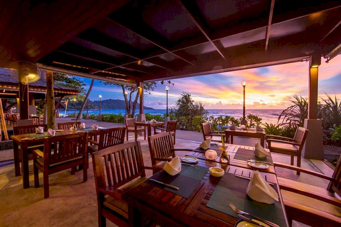 Außenbereich des Katathani Phuket Beach Resorts zum Essen mit Blick auf den Ozean und Sonnenuntergang.