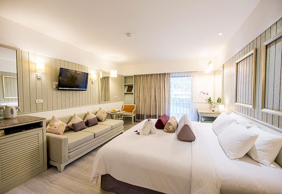 Hotelzimmer im Katathani Phuket Beach Resort mit großem Bett, Sofa, Fernseher und Fenstern.