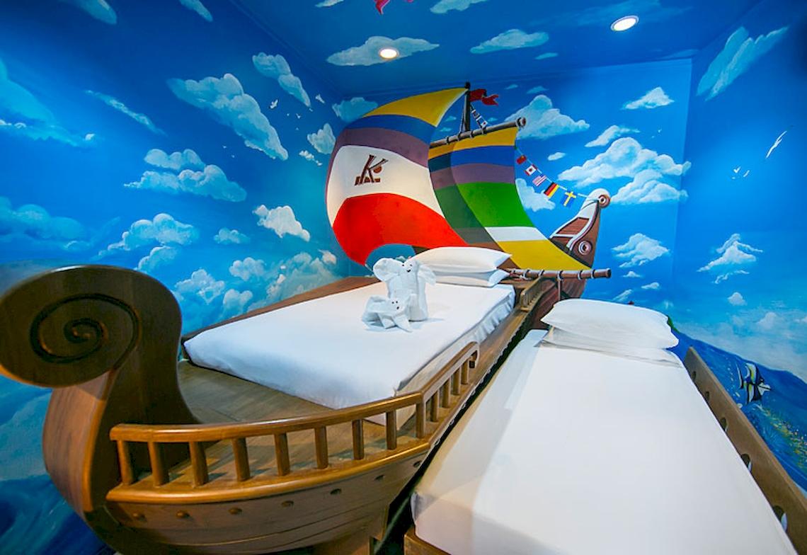 Doppelbett im Katathani Phuket Beach Resort, das als Schiff gestaltet ist, mit maritimem Wandbild.