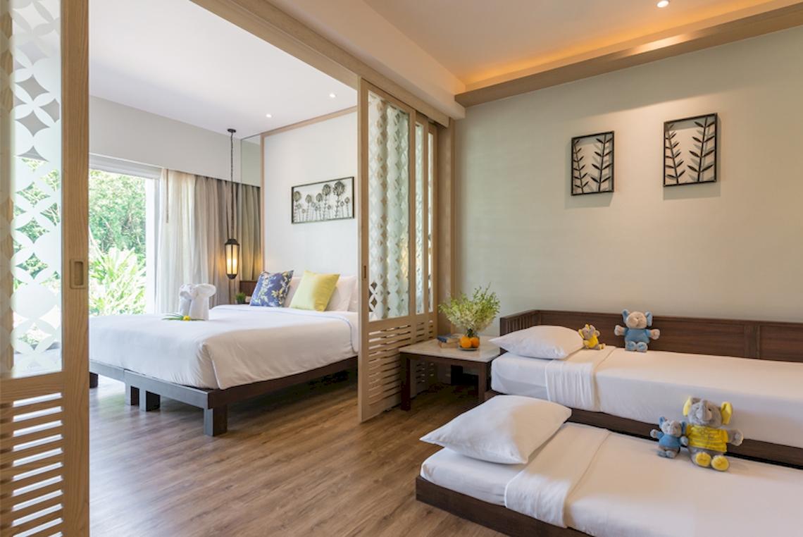 Innenansicht eines Zimmers im Katathani Phuket Beach Resort mit drei Betten und Dekofiguren.