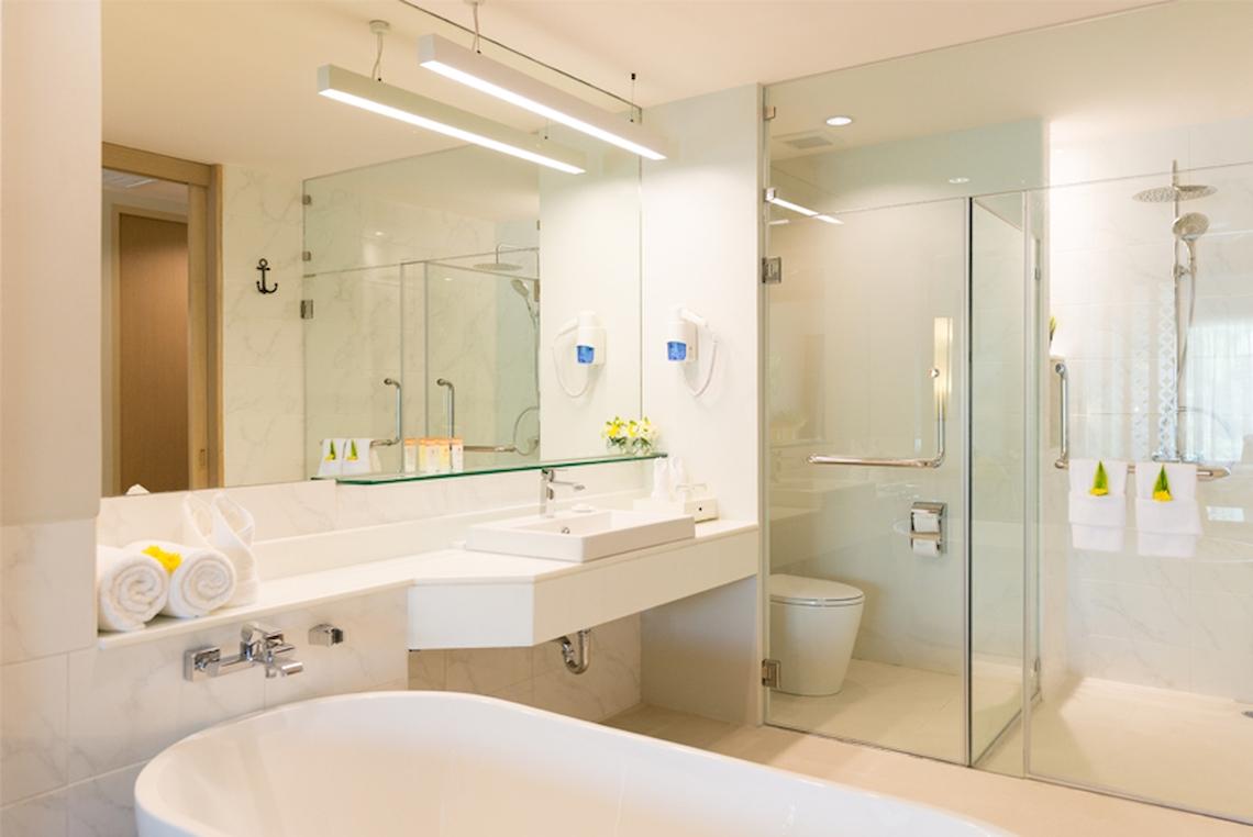 Badezimmer im Katathani Phuket Beach Resort mit Badewanne, Dusche und Waschbecken.