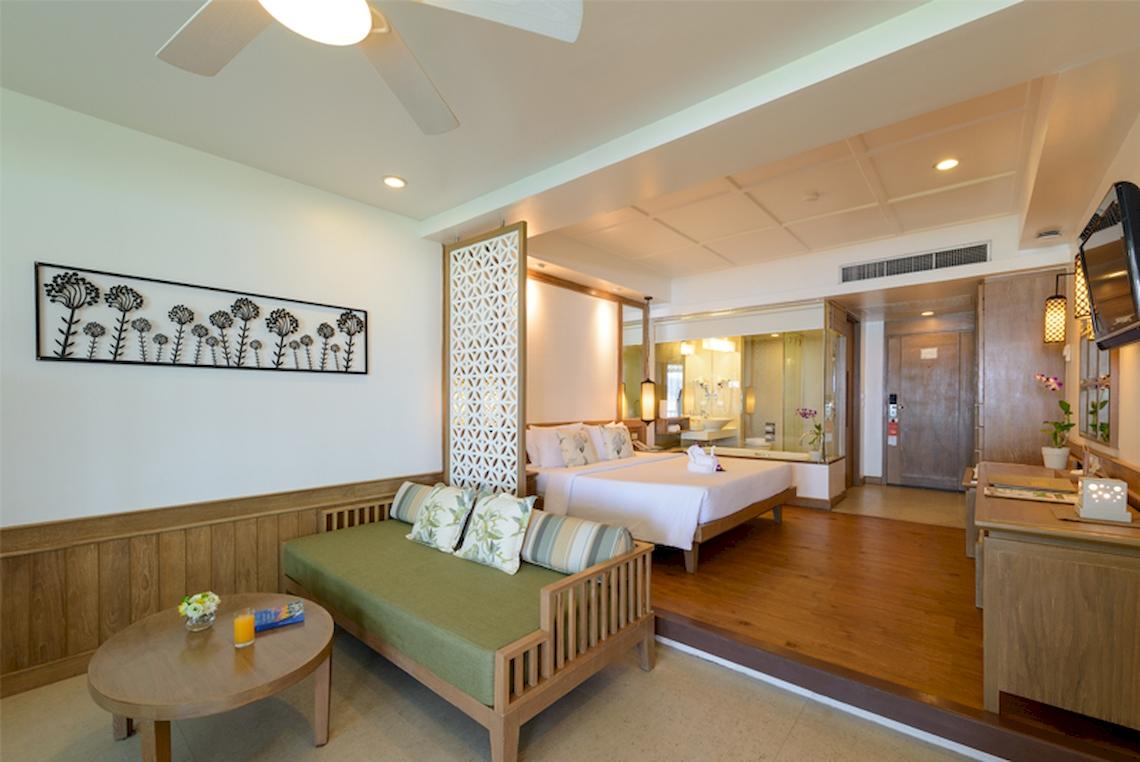 Innenansicht der Suite im Katathani Phuket Beach Resort mit Bett, Sofa und Schreibtisch.