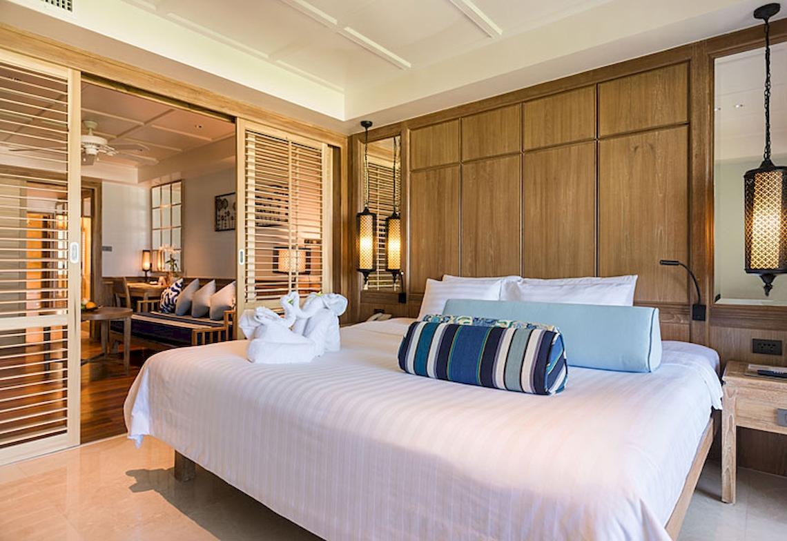 Schlafzimmer im Katathani Phuket Beach Resort mit gemustertem Kissen und frischen Handtüchern.