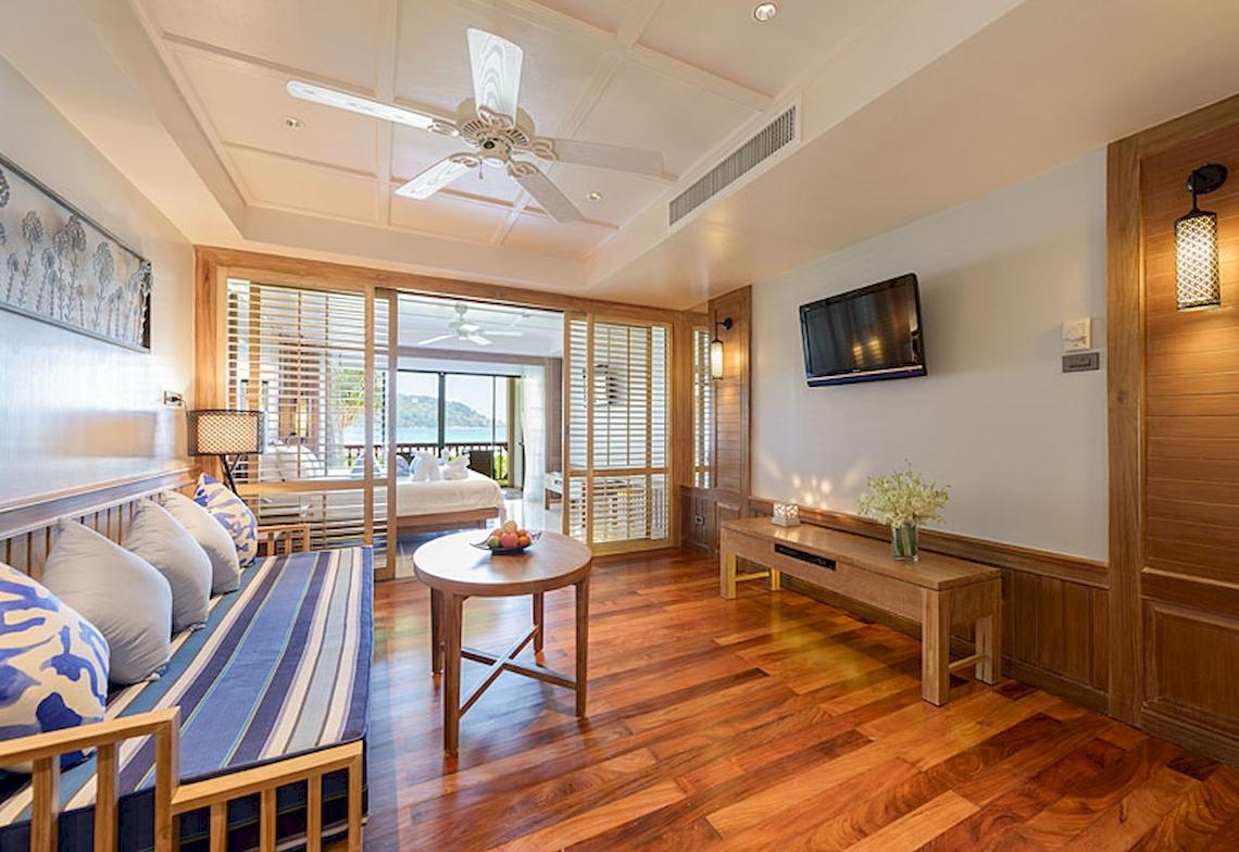 Inneneinrichtung eines Zimmers im Katathani Phuket Beach Resort mit Holzboden, Möbeln und Fernseher.