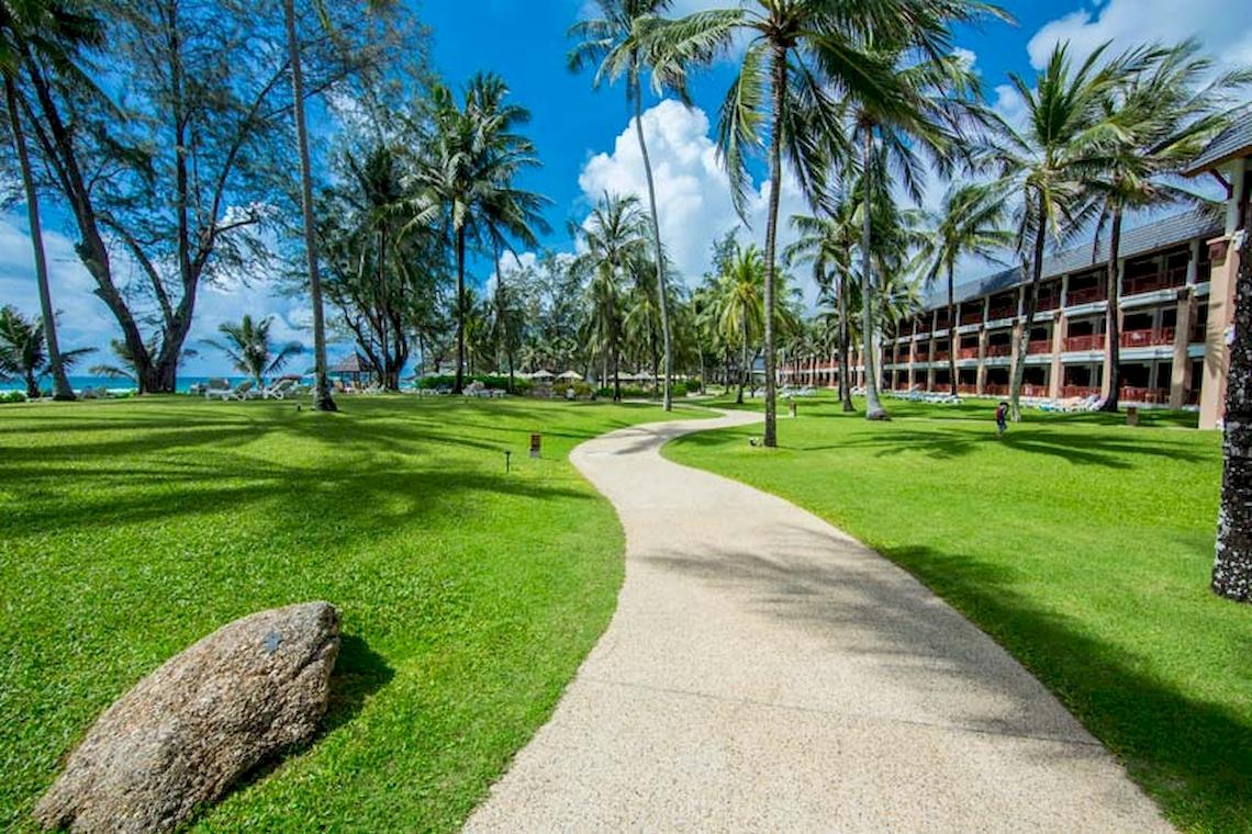Parkweg zum Katathani Phuket Beach Resort mit grünem Rasen und Palmen