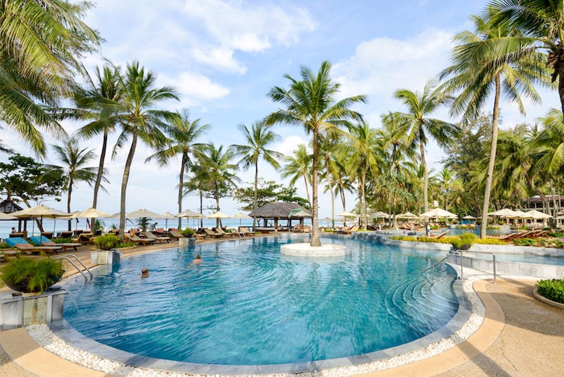 Ein großer Swimmingpool im Katathani Phuket Beach Resort mit vielen Palmen und Sonnenliegen.