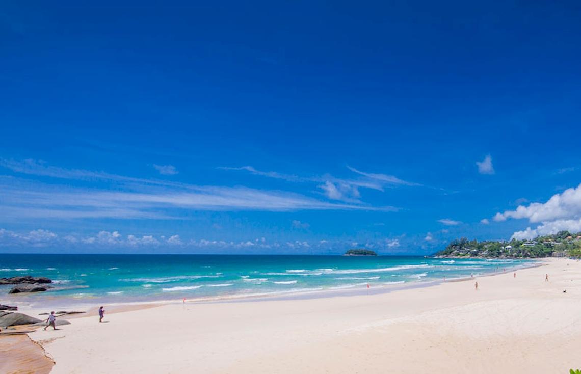Strand des Katathani Phuket Beach Resorts mit blauem Himmel und kristallklarem Wasser