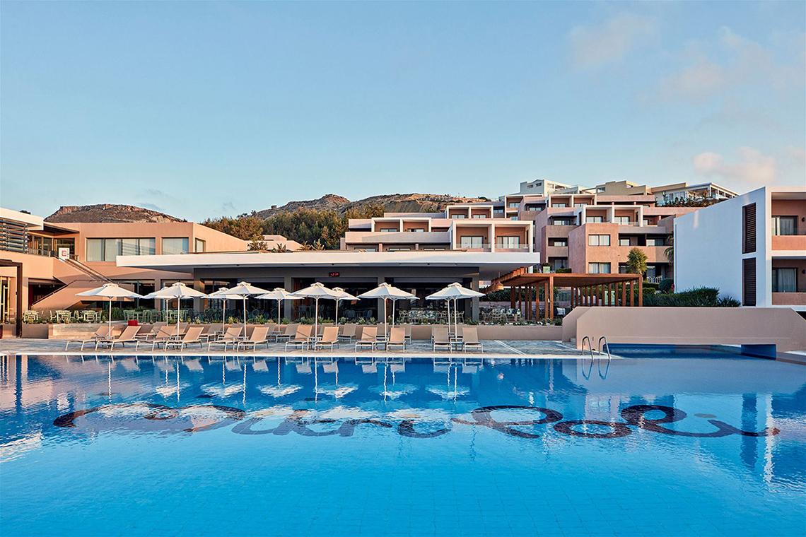 Außenbereich des Atlantica Mikri Poli Kos Hotels mit Swimmingpool und Sonnenliegen.