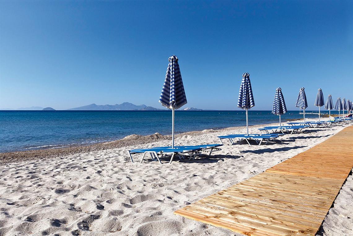 Strandszene mit Sonnenliegen und Sonnenschirmen am Atlantica Mikri Poli Kos Hotel
