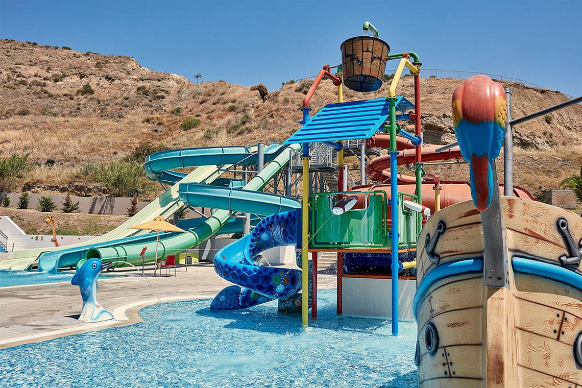 Wasserpark im Atlantica Mikri Poli Kos Hotel mit bunten Rutschen und einem Boot.