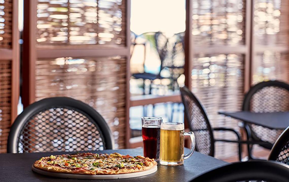 Pizza und Getränke auf einem Tisch im Restaurant des Atlantica Mikri Poli Kos.