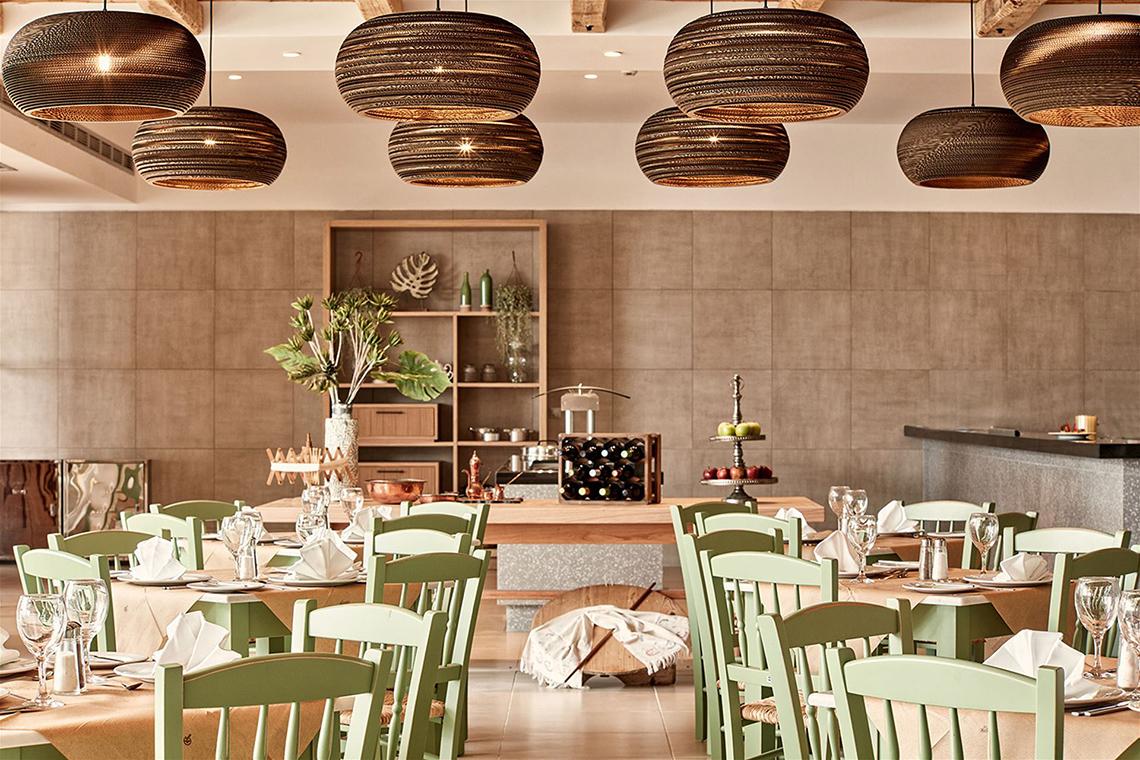 Innenansicht des Restaurants des Atlantica Mikri Poli Kos Hotels mit grünen Stühlen und Holztischen.