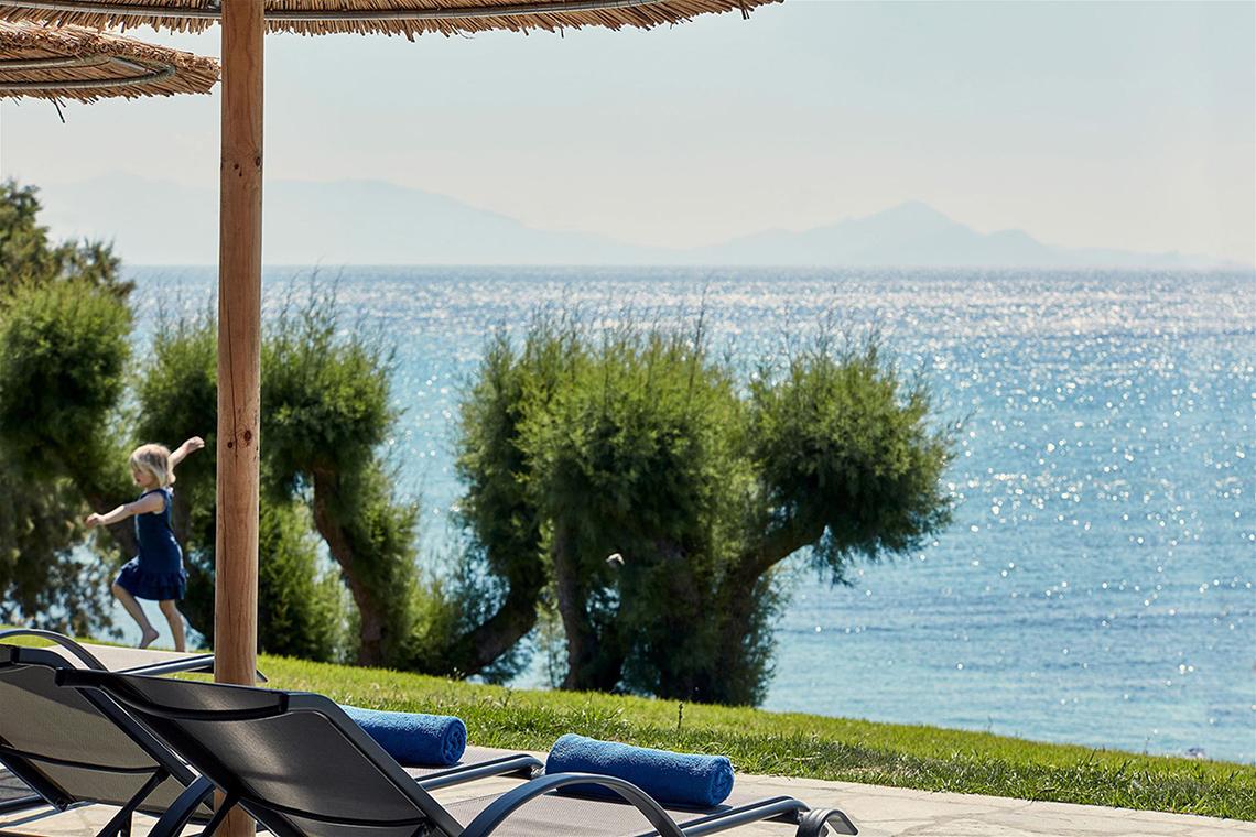 Ein kleiner Junge spielt auf dem Spielplatz am Atlantica Mikri Poli Kos Hotel mit Blick auf das Meer.