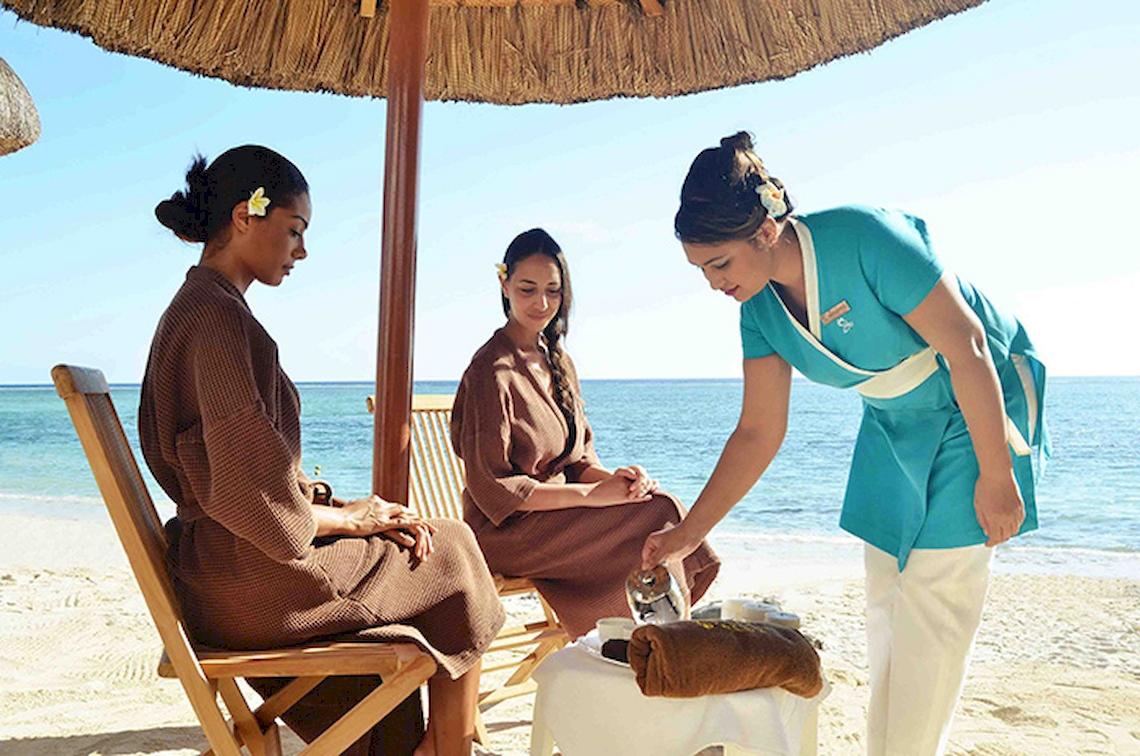 Massage-Service am Strand beim Pearle Beach Resort & Spa mit drei Frauen, eine serviert Tee.