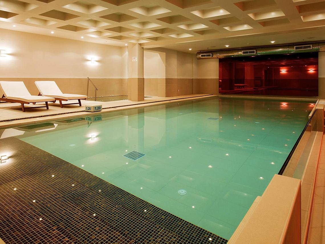 Innenpool im Pearle Beach Resort & Spa mit zwei Liegen und türkisfarbenem Wasser.
