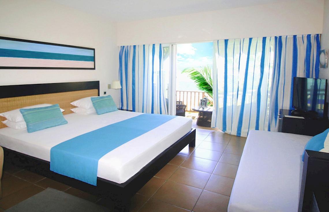Doppelbett mit Balkon im Pearle Beach Resort & Spa mit Blick auf den Ozean.