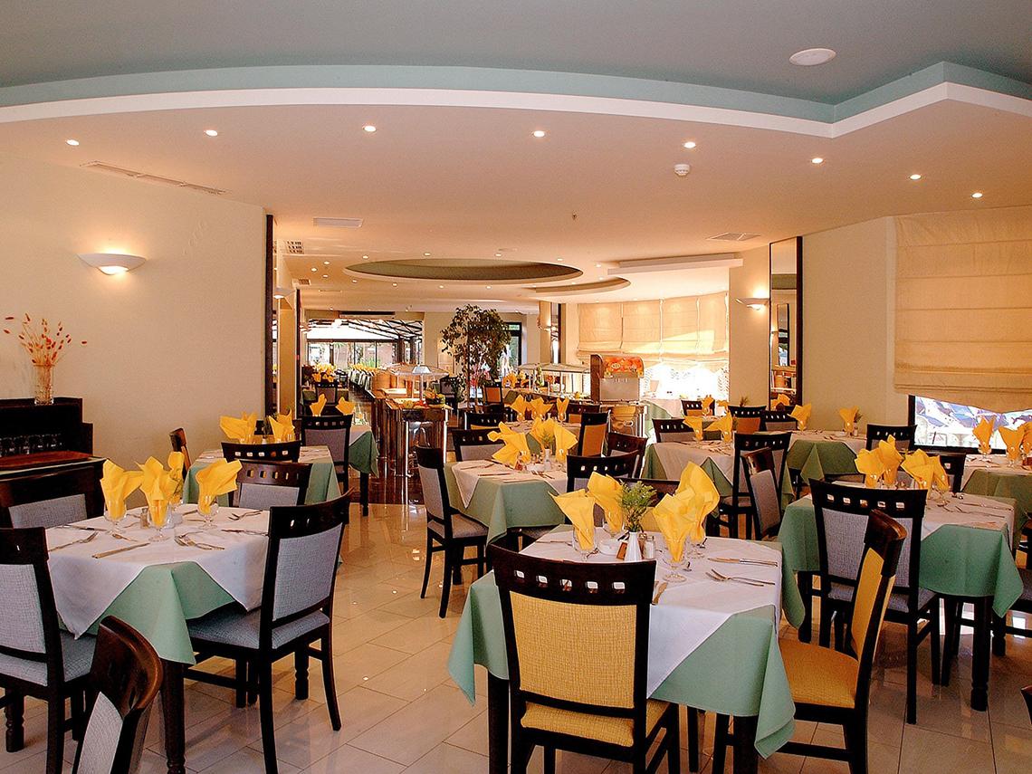 Innenansicht des Restaurants im Pearle Beach Resort mit gedeckten Tischen und Stühlen.