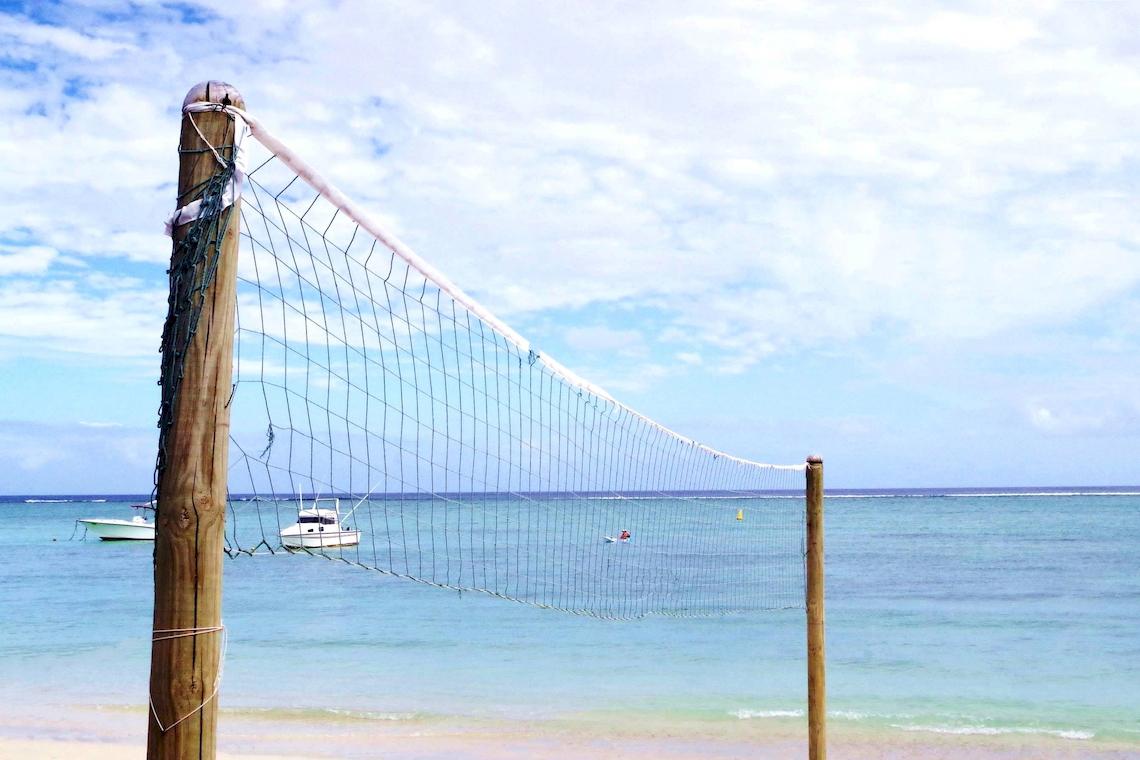 Ein Volleyballnetz am Strand mit Blick auf den Himmel und das Meer.