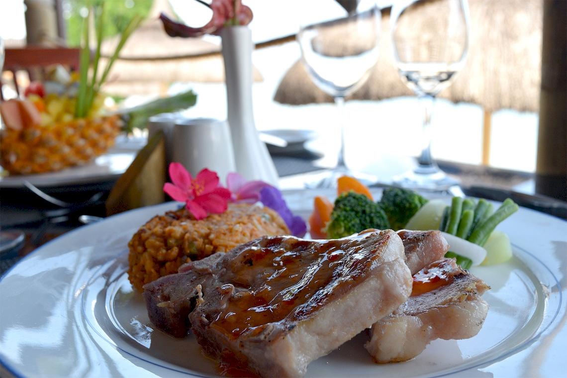 Ein reich gedeckter Tisch im Pearle Beach Resort & Spa mit einem Gericht aus Fleisch, Reis und Gemüse.