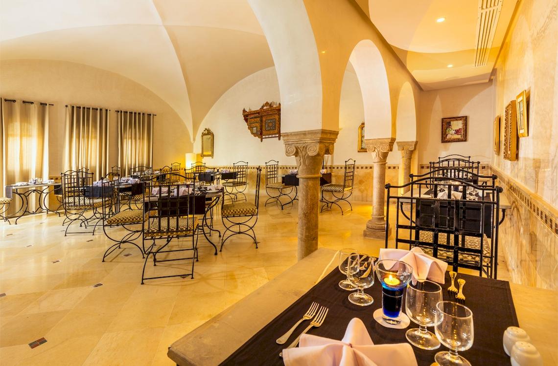 Innenansicht des Restaurants des Ulysse Djerba Thalasso & Spa Hotels mit Tisch, Stühlen und Kerzen.