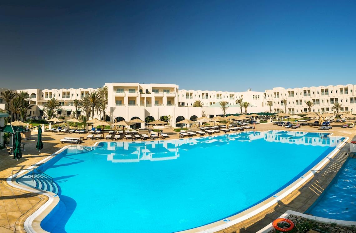 Außenpool des Ulysse Djerba Thalasso & Spa Hotels mit weißen Gebäuden und vielen Sonnenliegen