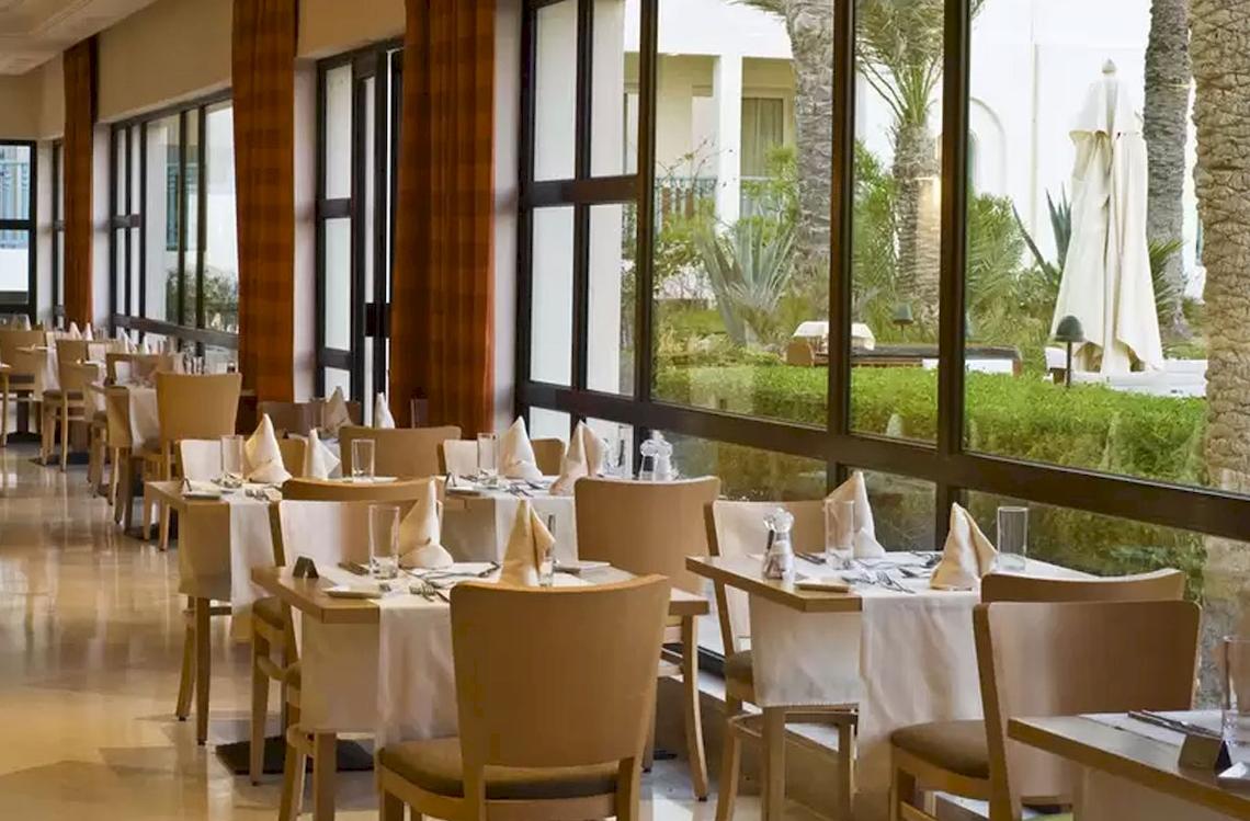 Restaurant des Ulysse Djerba Thalasso & Spa mit gedeckten Tischen und Blick auf den Garten