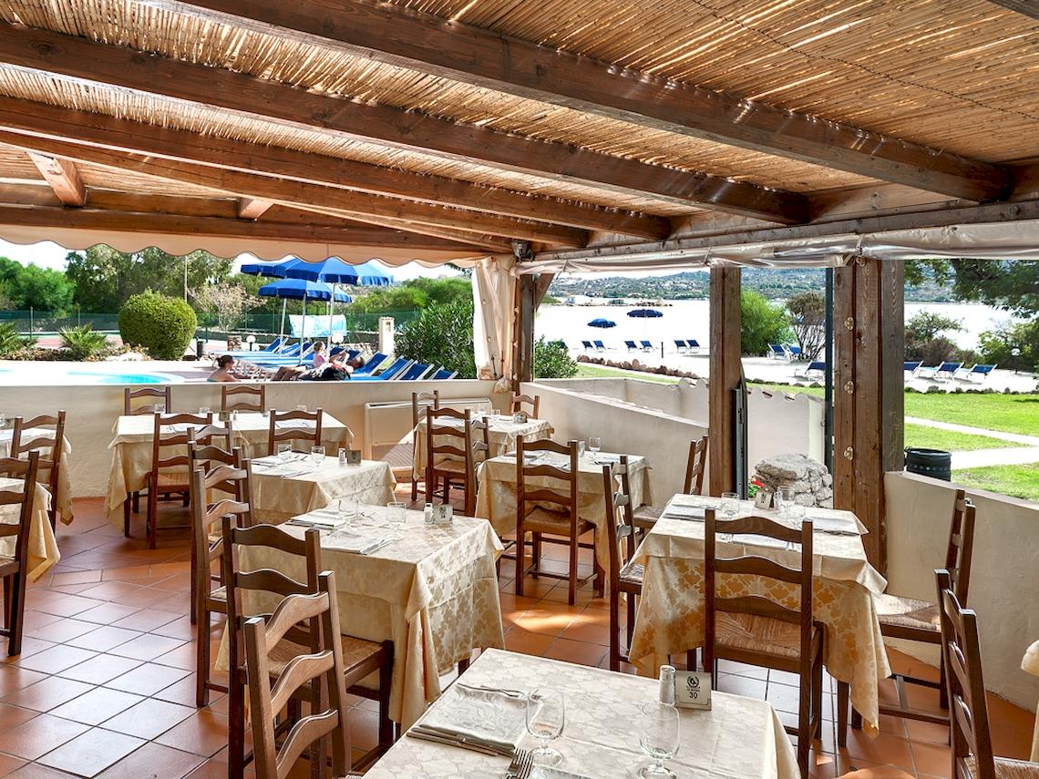 Innenansicht des Restaurants im Colonna Hotel Du Golf mit Tischen und Stühlen, Blick auf den Pool und die Terrasse.