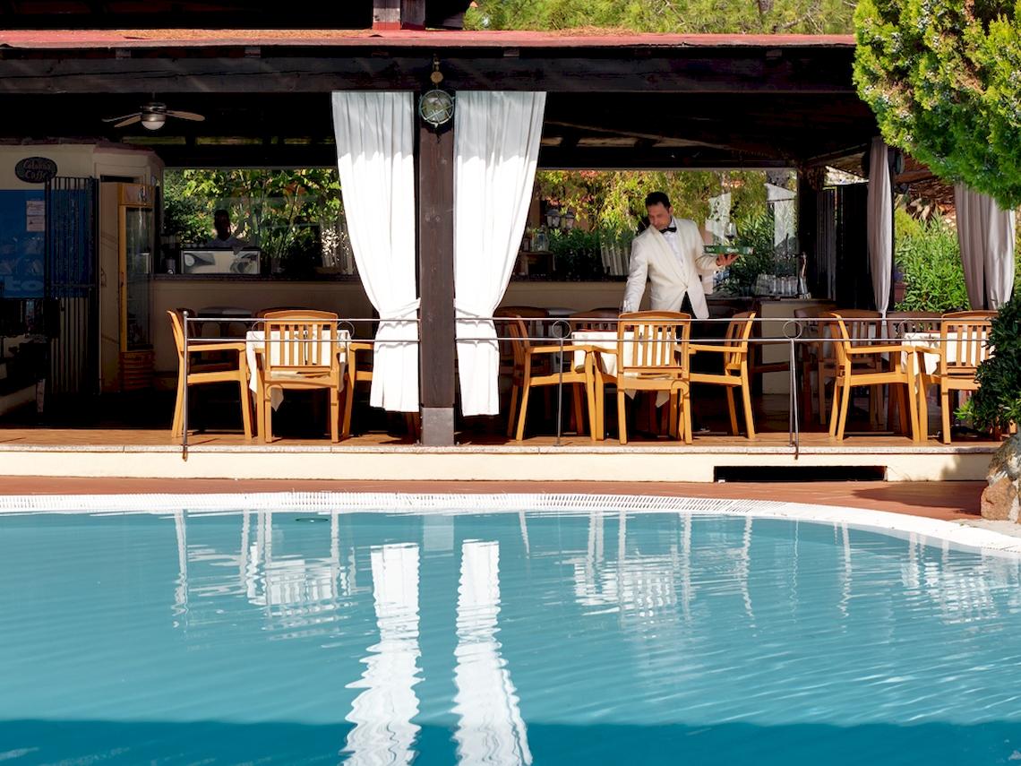 Ein Butler serviert im Freien am Poolbereich des Colonna Hotel Du Golf.