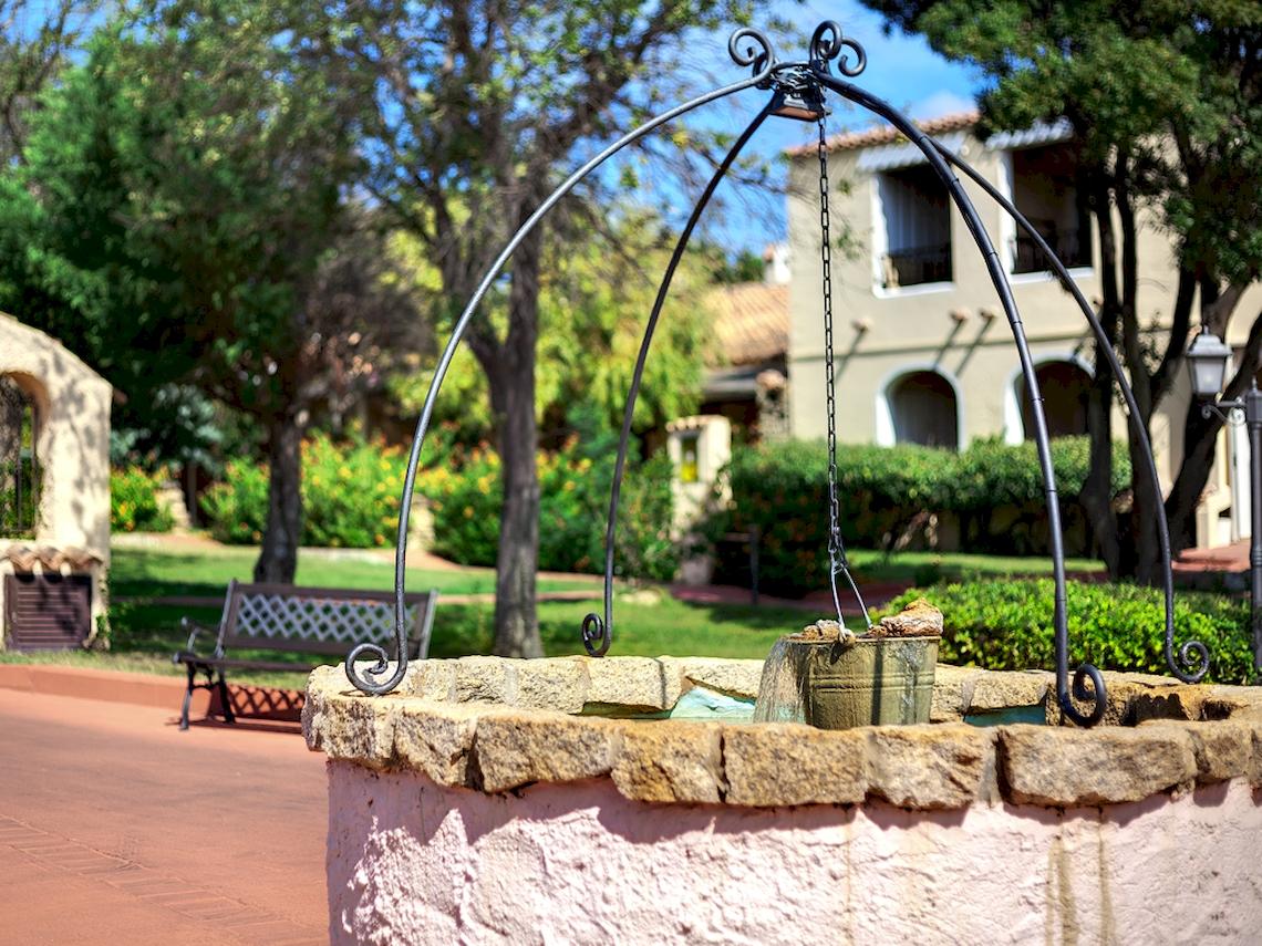Brunnen vor dem Colonna Hotel Du Golf mit Wasser und Bäumen im Hintergrund.