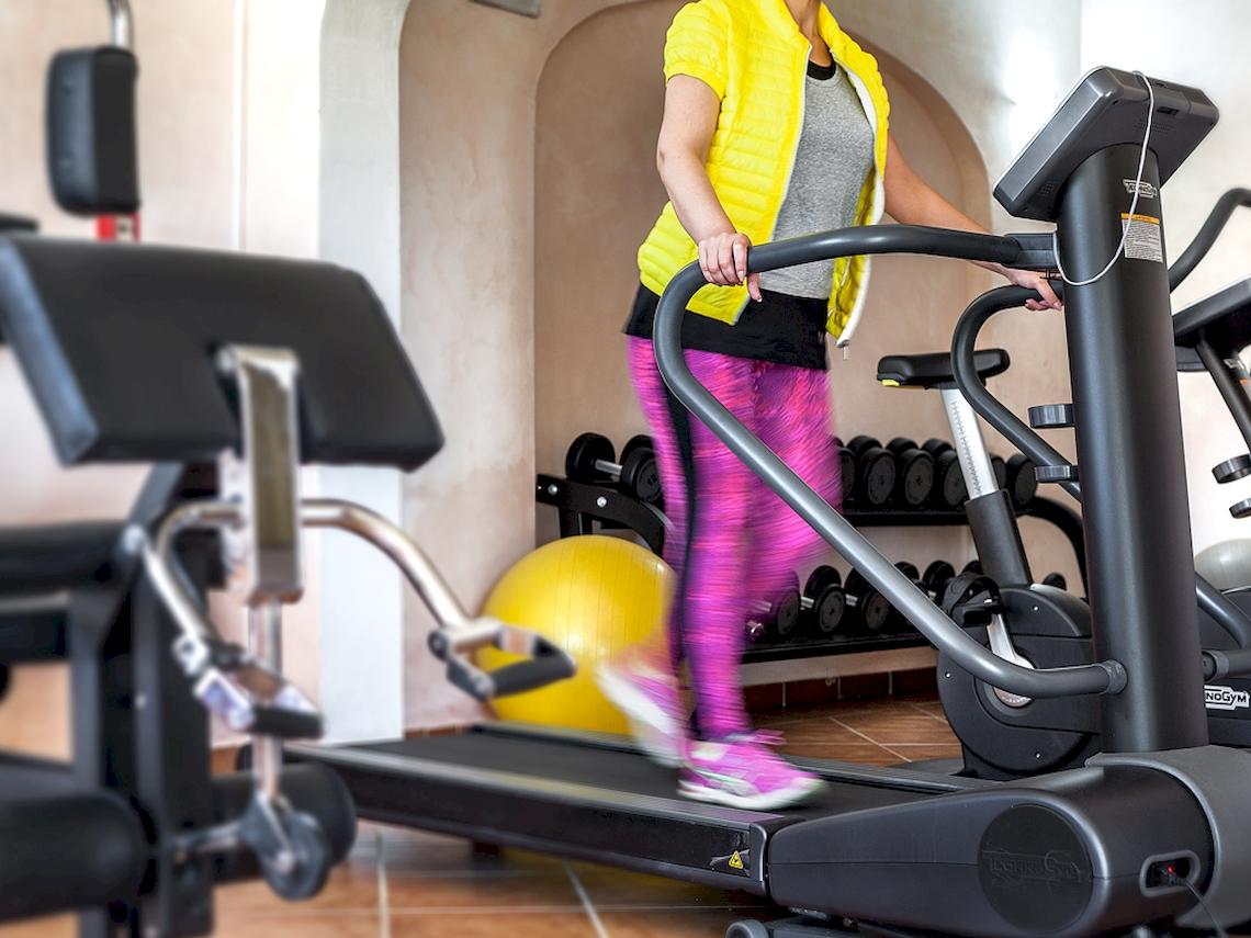 Frau im Colonna Hotel Du Golf Fitnessbereich auf dem Laufband.