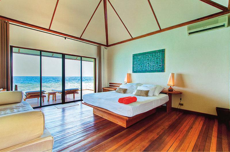 Schlafzimmer im Nakai Maayafushi Resort mit Blick auf das Meer und Möbeln.