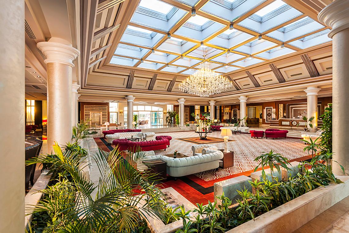 Innenansicht der Lobby des Rixos Sharm El Sheikh Hotels mit einem großen Kristallkronleuchter und modernen Möbeln.