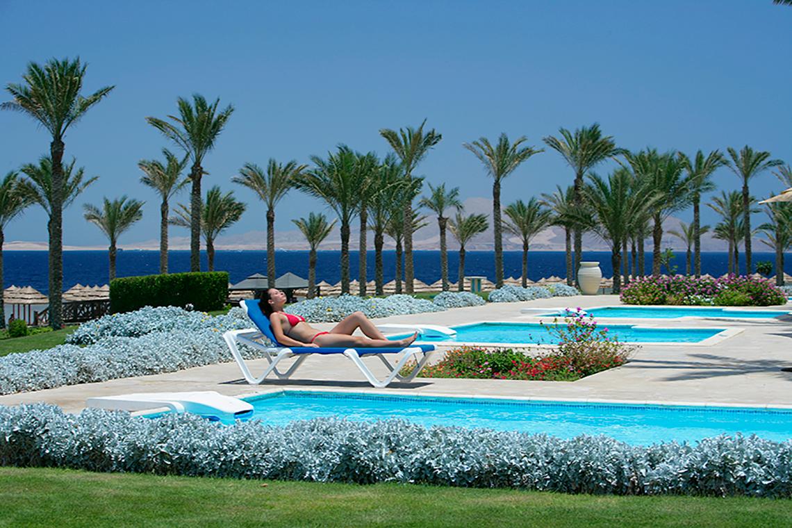 Frau im roten Bikini liegt auf einer Liege am Pool im Rixos Sharm El Sheikh